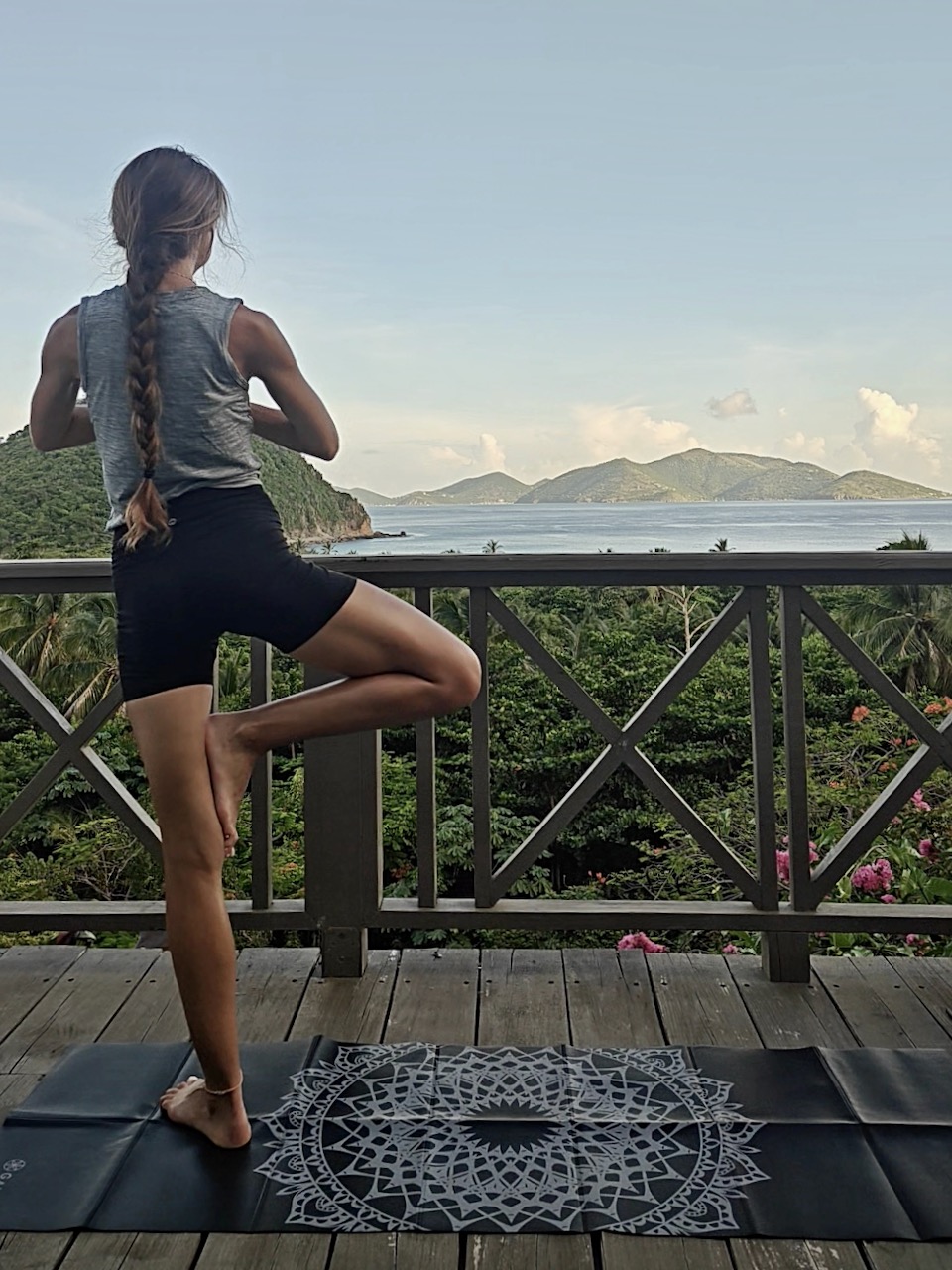 A woman enjoys a yoga session on a deck, overlooking the beautiful ocean, connecting with nature and finding inner peace.